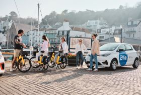 A group of friends on EVieBikes meeting a friend in an EVie Renault Zoe.