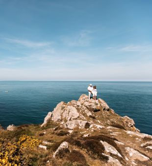 A couple walking on the rugged north coast of Jersey