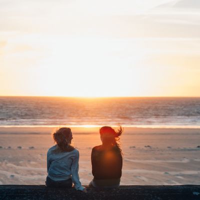 two friends sit on the sea wall overlooking St. Ouen
