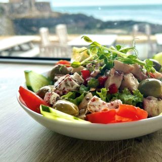 Bowl of greek salad in front of window overlooking Archirondel bay